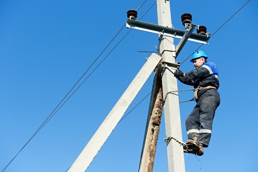 Electrical lineman working at the top of the pole