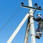 Electrical lineman working at the top of the pole